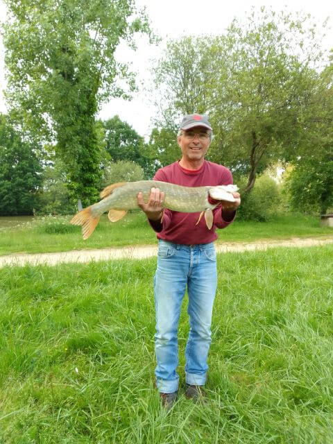 Pêcheur souriant présentant fièrement un gros brochet pêché à l'Étang des Grenières à Vairé